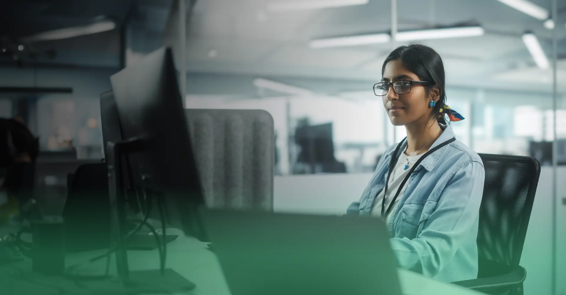 Woman wearing glasses working on her desk and looking at a monitor